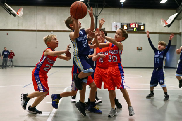A Grizzlies 8U attempts a layup as three Thunder defenders try to stop him in a game earlier this season. Enquirer photo by Jim Meadows